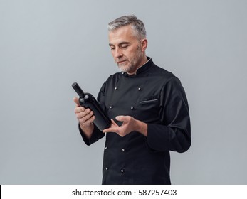 Professional Chef And Sommelier Holding A Bottle Of Wine And Reading A Label, Wine Culture Concept