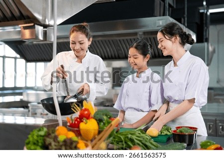 Professional chef is teaching young culinary class student to prepare fresh ingredient for the meal inside the restaurant kitchen for fine dining gourmet and cooking school