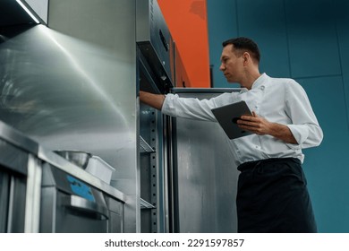 Professional chef using tablet computer recipes while working in modern kitchen cooking concept - Powered by Shutterstock