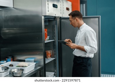 Professional chef using tablet computer recipes while working in modern kitchen cooking concept - Powered by Shutterstock