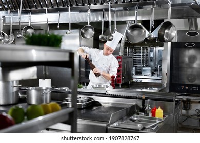 Professional chef in white uniform salts king prawns. Wooden salt grinder - Powered by Shutterstock