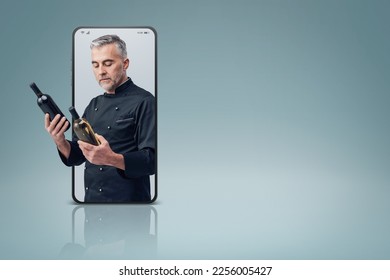 Professional chef and wine expert comparing wine bottles  in a smartphone videocall and smiling, online  service concept - Powered by Shutterstock