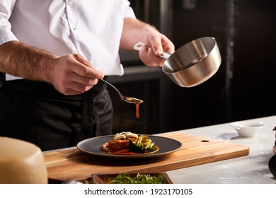 Professional Chef-cook Decorating Dish In Restaurant Kitchen Alone. Man In White Apron Makes Finishing Touch On DIsh. Culinary, Restaurant, Gourmet Concept - Shutterstock ID 1923170105