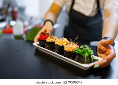 professional chef's hands making sushi roll in a restaurant kitchen - Shutterstock ID 2279598349
