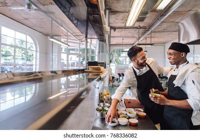 Professional chefs working in restaurant kitchen. Smiling chefs cooking food at commercial kitchen. - Powered by Shutterstock