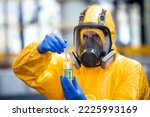 Professional chemical worker in protection suit and gas mask handling dangerous material inside chemicals production plant.