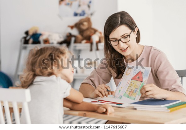 A professional child\
education therapist having a meeting with a kid in a family support\
center.