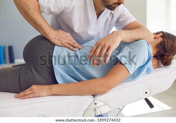 Professional chiropractor or\
physiotherapist helps to heal a young woman\'s back. Doctor fixes\
the patient lying on a couch of a modern rehabilitation clinic\
Concept of physical\
rehabilitation.