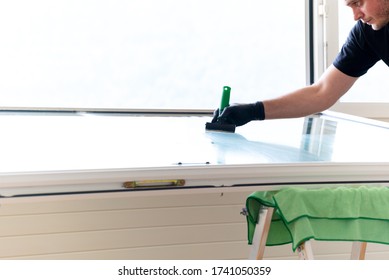 A Professional Cleaneer Using A Diamond Blade Scraper To Clean A Window