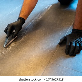 A Professional Cleaner Cleaning Grout With A Brush Blade And Foamy Soap On A Gray Tiled Bathroom Floor