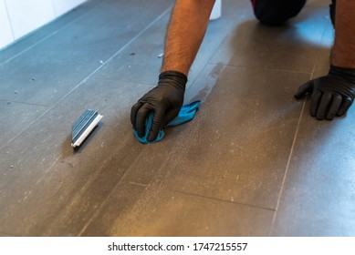 A Professional Cleaner Cleaning Grout With A Brush Blade And Foamy Soap On A Gray Tiled Bathroom Floor