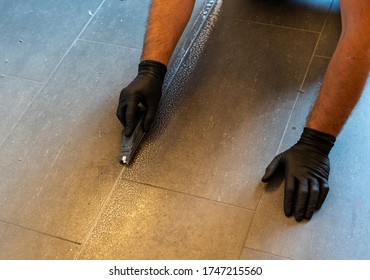 A Professional Cleaner Cleaning Grout With A Brush Blade And Foamy Soap On A Gray Tiled Bathroom Floor