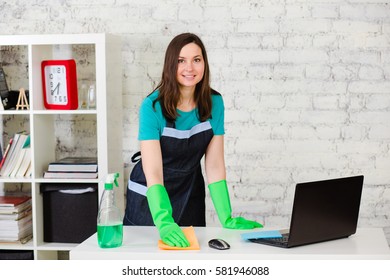 Professional cleaner cleans leans the house using a sponge and spray, standing in bright modern room