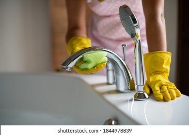 Professional Cleaning Of The Bathroom And Toilet. Cleanliness And Hygiene At Home. Cleaning Service And Housekeeping. Hand In Green And Yellow Latex Gloves. Rubbing The Bathroom And Taps