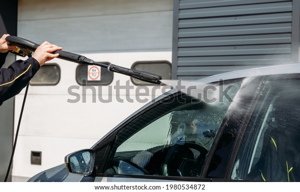 Professional cleaning\
and cleaning of cars from pollution. A man works out with a\
background of high pressure\
water