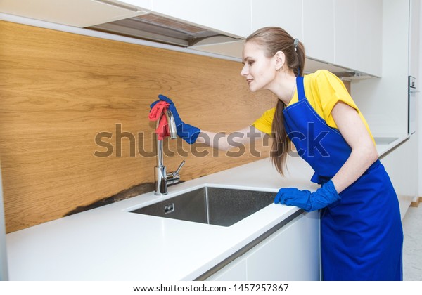 professional
cleaning service. Two women in working uniform, in aprons, divide
the cleaning of the kitchen of a private house, cottage. washing
the refrigerator, tap, sink. Wash
floor.