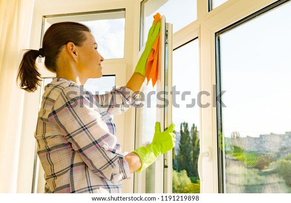Professional cleaning service. Woman housekeeper\
cleaning windows.