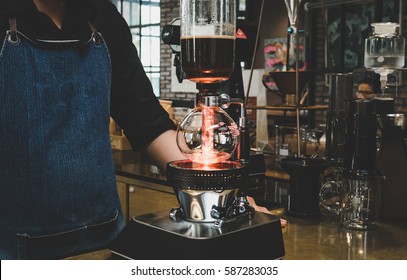Professional coffee maker - Barista using coffee siphon brewing hot espresso at coffee shop