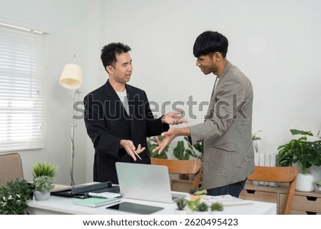 Professional Collaboration and Document Review. Two men discussing key points while reviewing documents in a modern office.