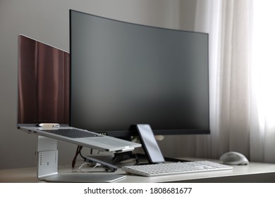 
professional computer workstation consisting of a laptop and a large curved monitor on a white desk