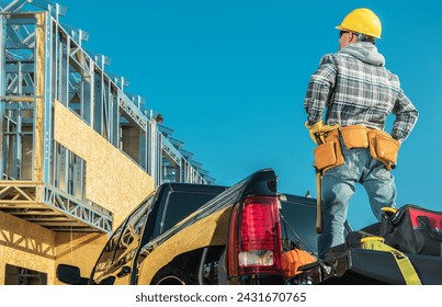 Professional Construction Contractor Worker Taking a Look on the Skeleton Frame of a Building While Staying on a Pickup Truck Bed - Powered by Shutterstock