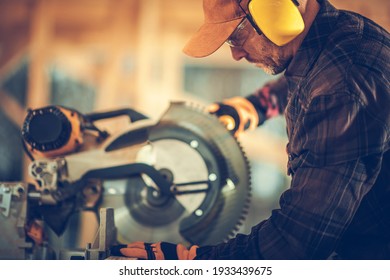 Professional Construction Contractor Worker Using Powerful Circular Wood Saw in Construction Zone. Wearing Safety Glasses and Noise Reduction Headphones. Industrial Theme.
