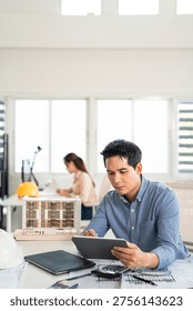 Professional construction engineer checking details on blueprint in construction site office.