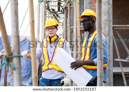 Professional Construction and  Engineer team Working on workplace. Professional black architect and construction worker working look at blueprint plan on site.