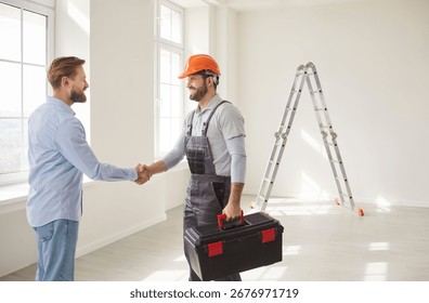 Professional construction worker and man client confirming agreement about house renovation or architectural project, shaking hands while posing in empty room, agree about future design