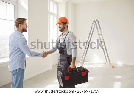 Professional construction worker and man client confirming agreement about house renovation or architectural project, shaking hands while posing in empty room, agree about future design