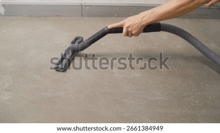 Professional construction worker performing thorough floor cleaning, removing dust and debris using powerful industrial vacuum cleaner in renovation workspace