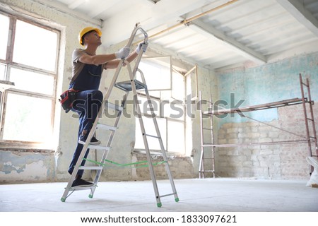Professional constructor on ladder in old building