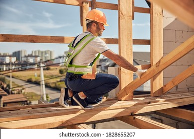 Professional Constructor Wearing Helmet While Preparing Frame For Covering Roof On The Future House