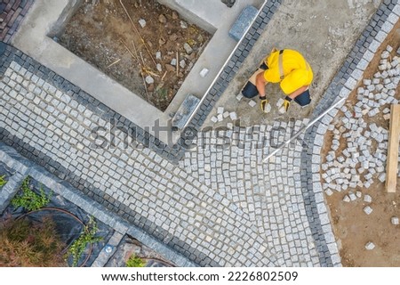 Professional Contractor Building Garden Brick Walkway of Granite Pavers. Backyard Design in Progress. Industrial Theme. Aerial View.