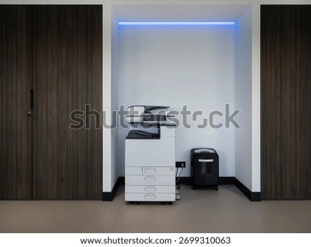 Professional copy machine and document shredder in minimalist office alcove with blue accent lighting