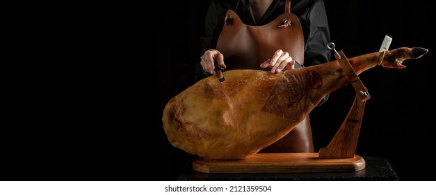 Professional cutter carving slices from a whole bone-in serrano ham, Spanish jamon iberico, Jamon Serrano, Bellota, Italian Prosciutto Crudo or Parma ham,