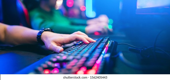 Professional cyber video gamer studio room with personal computer armchair, keyboard for stream in neon color blur background. Soft focus.