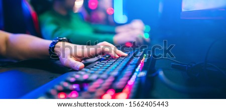 Professional cyber video gamer studio room with personal computer armchair, keyboard for stream in neon color blur background. Soft focus.