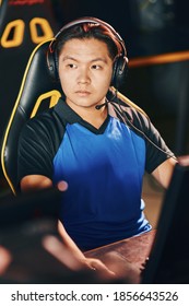 Professional Cybersport Gamer. Portrait Of A Young Asian Guy Wearing Headphones Looking Aside While Participating In ESport Tournament