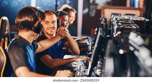 Professional cybersport team. Two happy male gamers shaking hands, celebrating success while participating in eSports tournament - Powered by Shutterstock