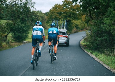 Professional cyclist race. Two cyclists behind the peloton in convoy of cars on the road. Cycling road Race, preparation for Tour race in France. - Powered by Shutterstock