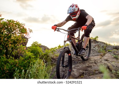 Professioneller Radfahrer, der das Bike Down Rocky Hill bei Sunset reitet. Extreme Sport Konzept.