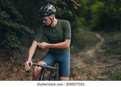 Professional cyclist in sport clothes, safety helmet and glasses preparing for morning cycling at green city park. Concept of active and healthy lifestyles.