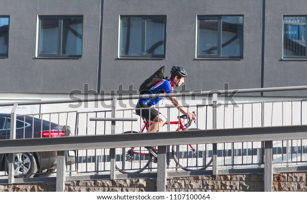 Professional cyclist in sportswear\
and a helmet rides a bike up the bridge over the background of\
architecture. Sports concept. Traveling around the city on a\
bicycle.