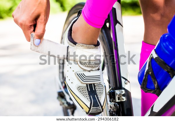 Professional cyclist triathlete\
buttons cycling shoes on the clasp to secure the foot on the pedal\
bike.