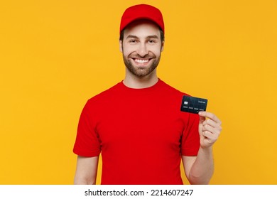 Professional Delivery Guy Employee Man In Red Cap T-shirt Uniform Workwear Work As Dealer Courier Hold In Hand Credit Bank Card Isolated On Plain Yellow Background Studio Portrait. Service Concept.