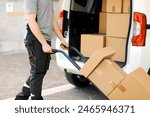 Professional delivery guy pushing a hand truck loaded with packages, express courier and delivery service concept