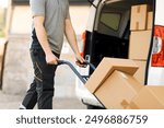 Professional delivery guy pushing a hand truck loaded with packages, express courier and delivery service concept