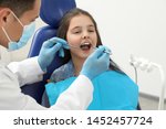 Professional dentist working with little girl in clinic