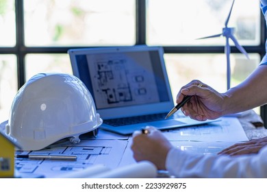Professional design engineers discuss calculations to use pure natural energy and installing solar panels and wind turbines on the roof of houses to generate electricity, energy saving and global warm - Shutterstock ID 2233929875